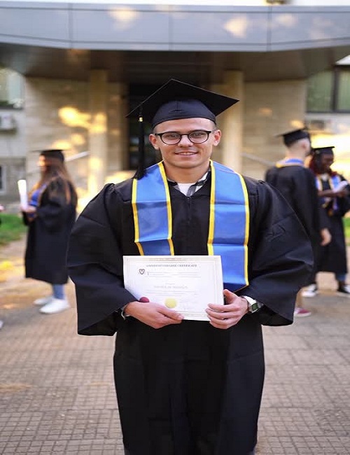 proud graduate holding his diploma while smiling at the camera